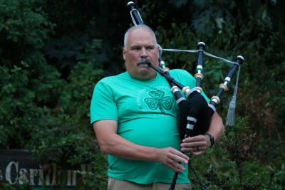 Man playing bagpipes with trees behind him